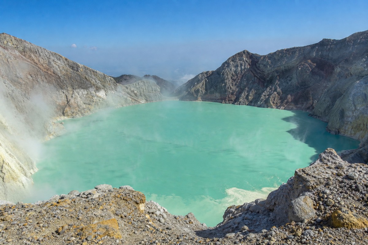 Turquoise sulfuric crater lake of Santa Ana volcano seen from the rim under a clear dry-season sky, pale rock walls all around