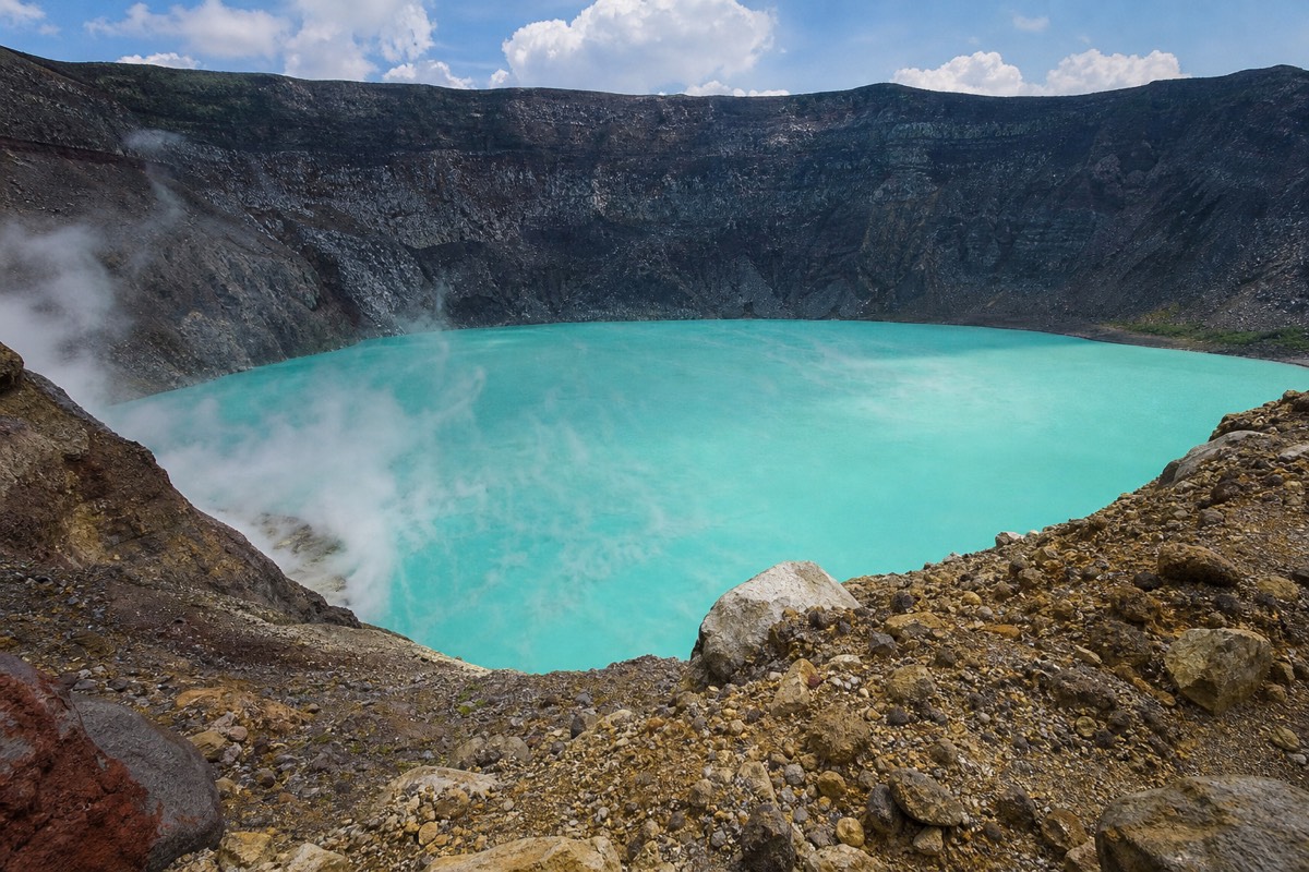 Santa Ana Volcano crater lake at full turquoise under high midday sun with pale steam drifting across the surface and the far crater wall in shadow