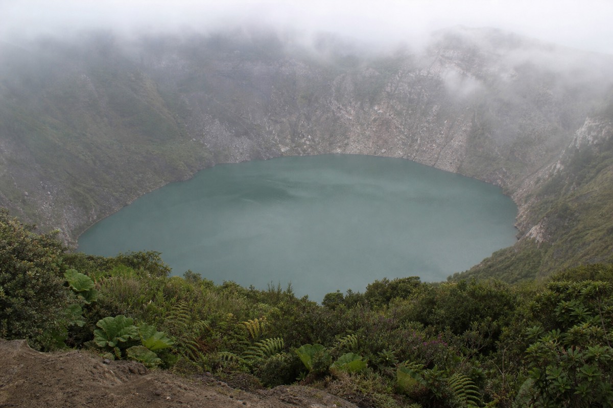 Santa Ana crater lake in a muted grey-green shade under low cloud with mist drifting across the crater walls