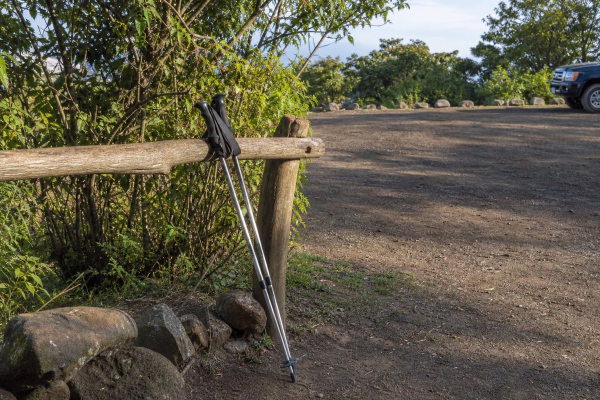 Morning light at a volcano trailhead gate near Cerro Verde with rental walking poles leaning on a wooden rail