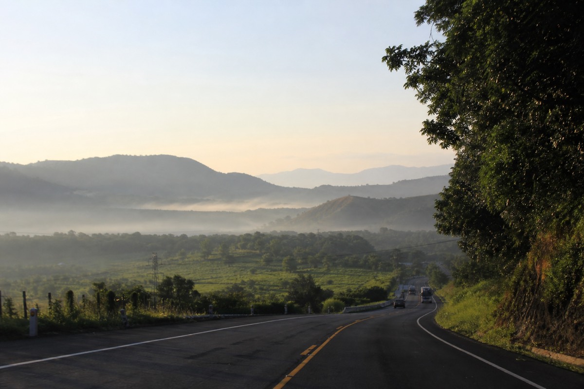 Early morning road heading west out of San Salvador toward the volcanic highlands with low haze over green hills