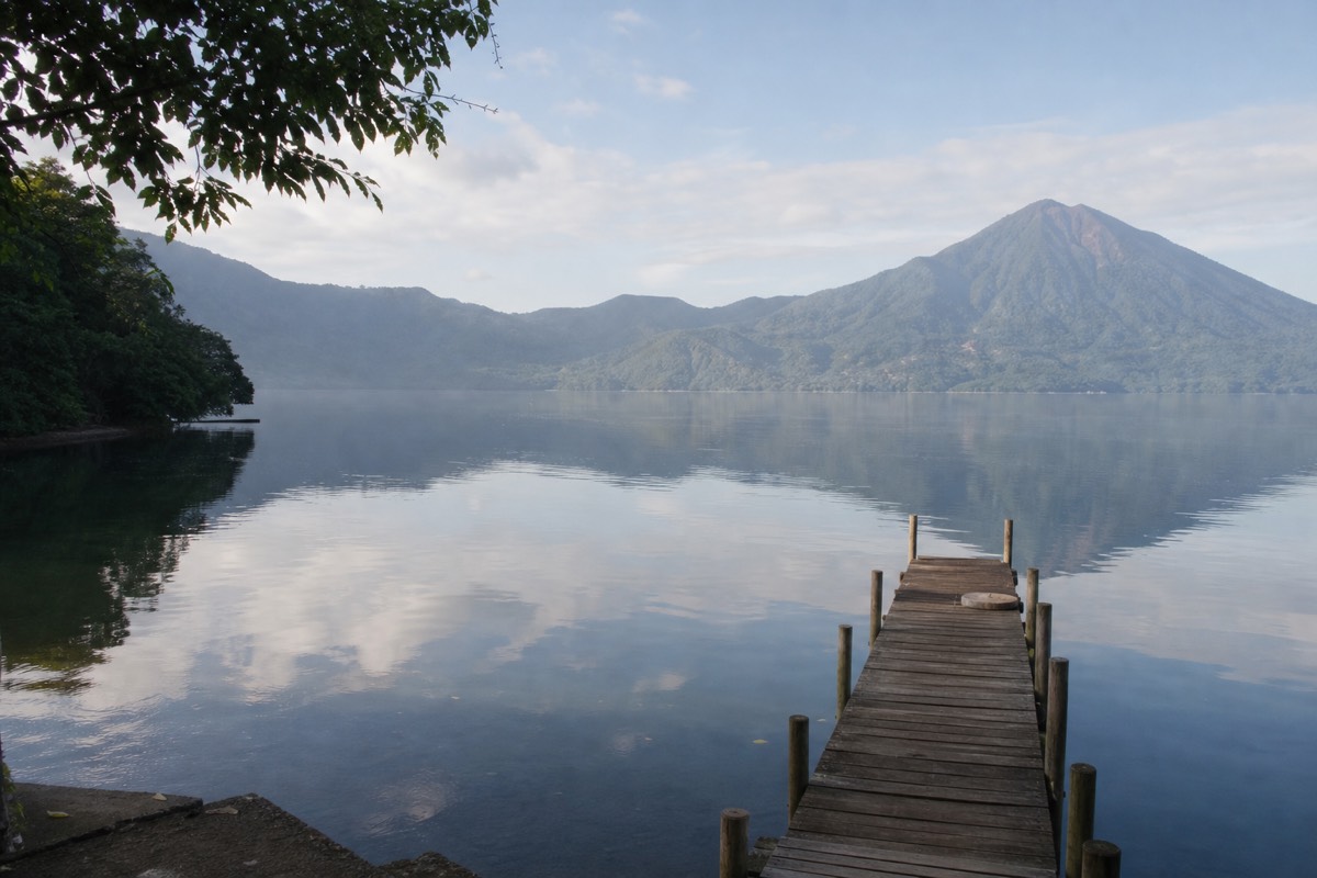 Calm morning water on Lake Coatepeque with the caldera rim and volcano slopes in soft light