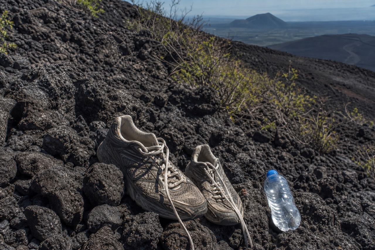 Hikers on the rocky upper section of the Santa Ana Volcano trail under a bright morning sky