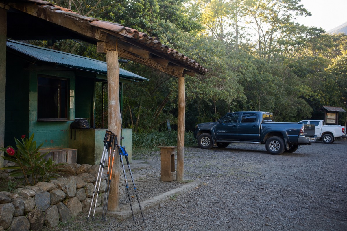 Small park entrance hut and parking area at the Santa Ana Volcano trailhead in early morning light with pickup trucks arriving