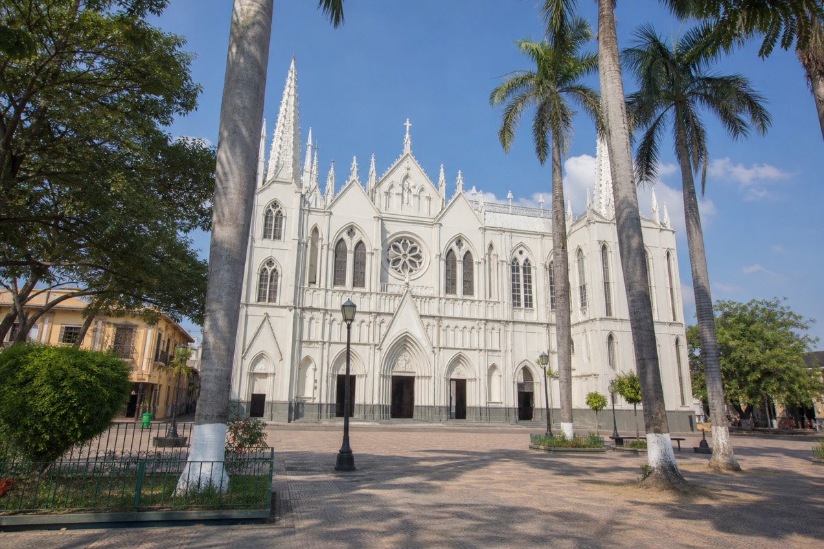 Sunlit main plaza of Santa Ana city with the ornate white cathedral facade and palm trees, a quiet weekday morning