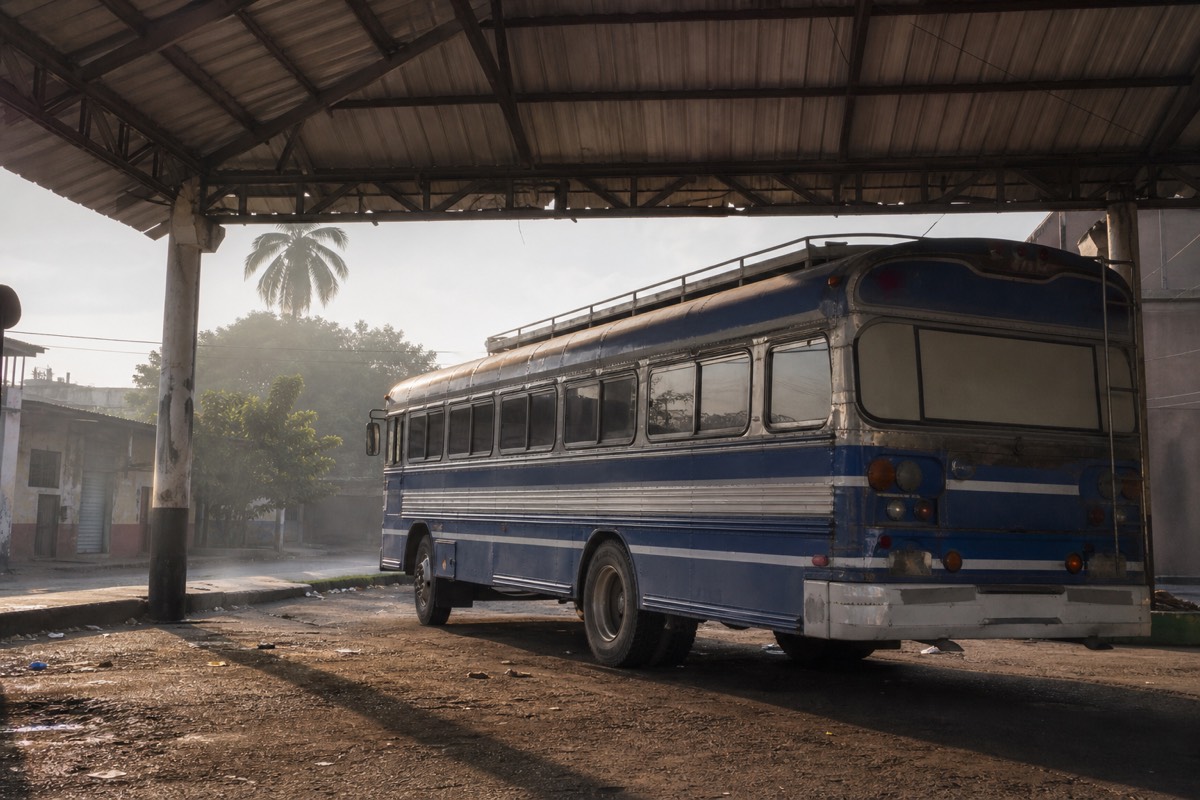 Early morning bus terminal in Santa Ana, El Salvador, with a bus waiting under a corrugated roof