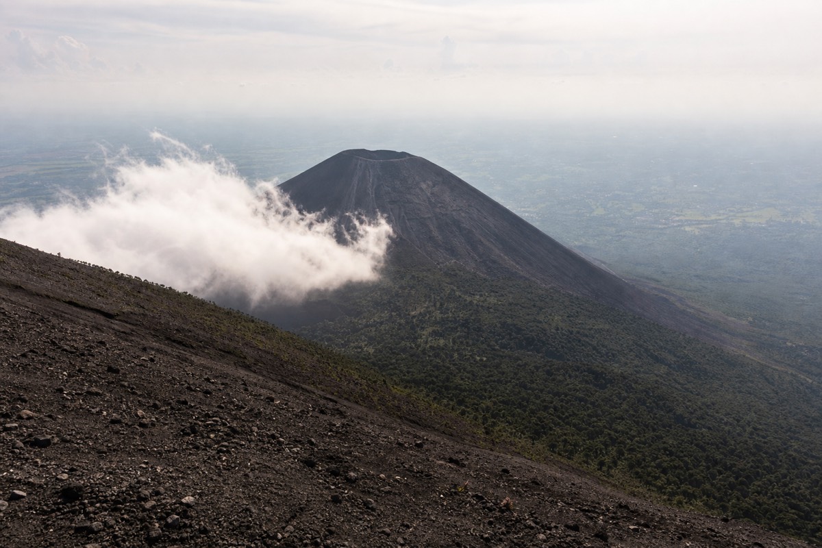 Bare black cone of Izalco volcano viewed from the upper Santa Ana trail with green forest below