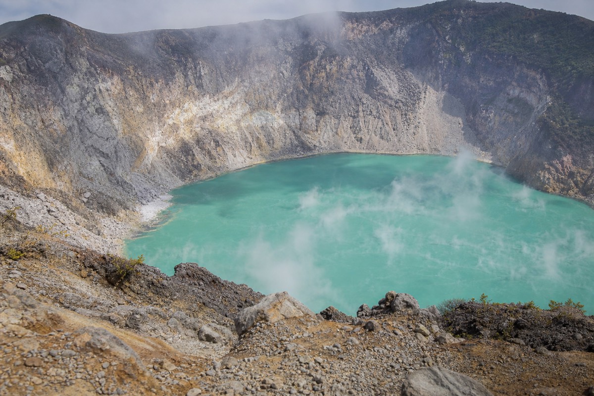 Steam drifting across the turquoise acidic crater lake of Santa Ana Volcano seen from the managed rim