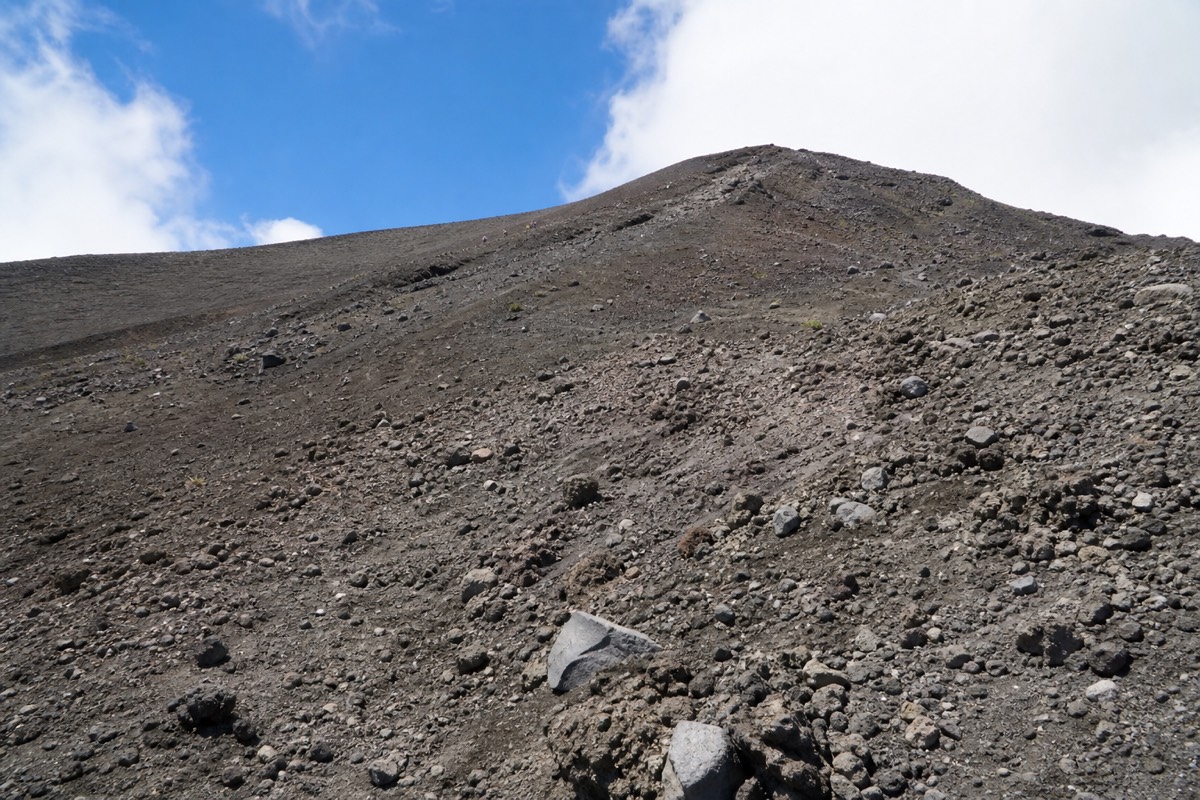 Loose grey volcanic rock on the upper section of the Santa Ana Volcano trail with the summit rim ahead