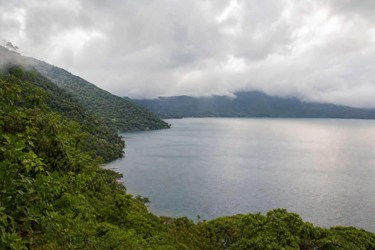 Green season cloud drifting over Lake Coatepeque with lush green caldera slopes and soft grey light on the water