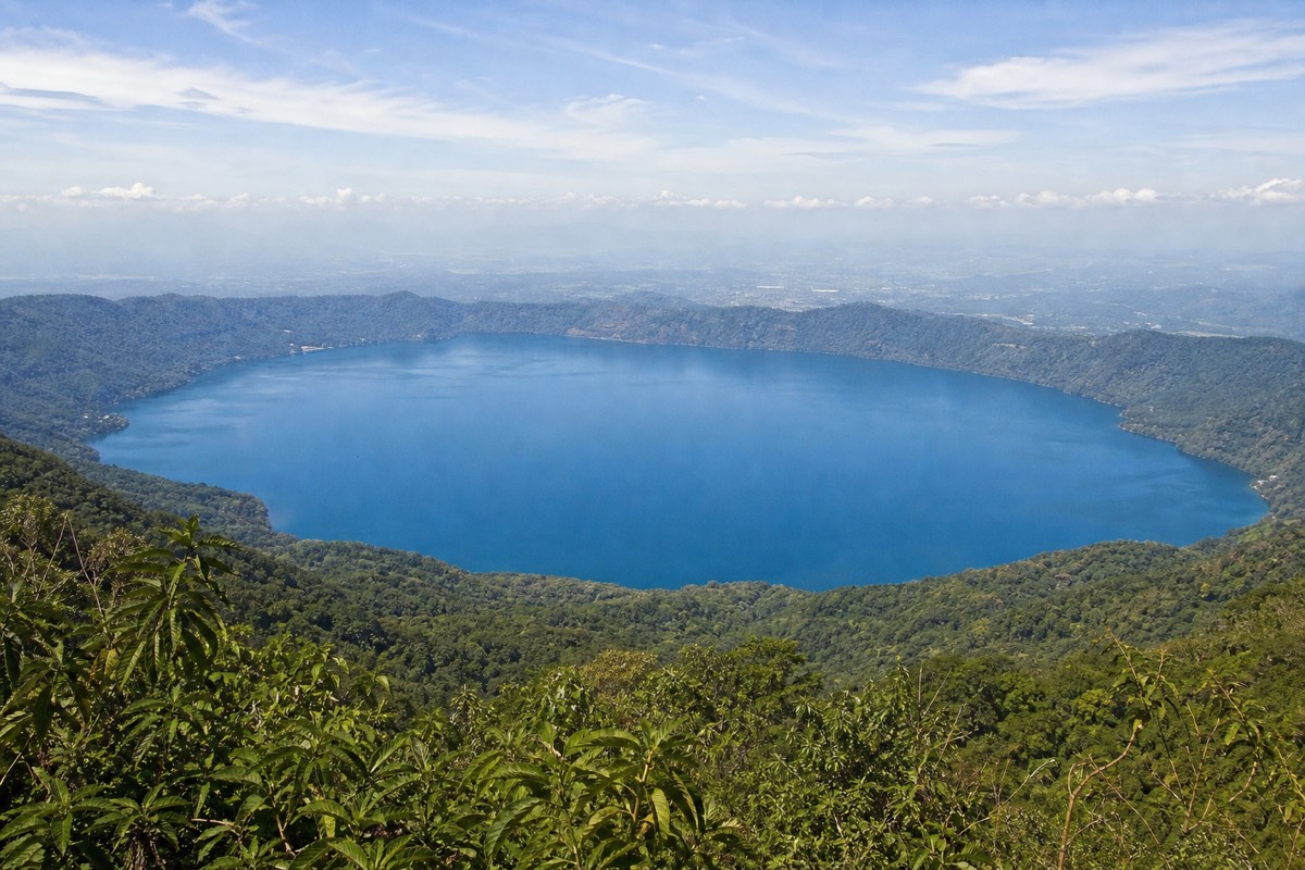 Lake Coatepeque seen from a viewpoint on the Santa Ana Volcano trail, a wide blue circle framed by green forested slopes