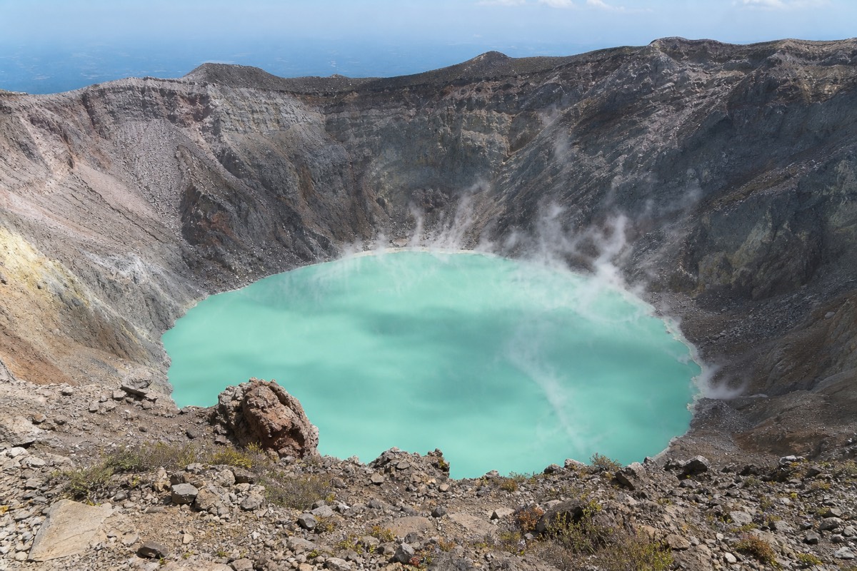 Steam lifting off the turquoise crater lake seen from the rocky summit rim of Santa Ana Volcano at midday