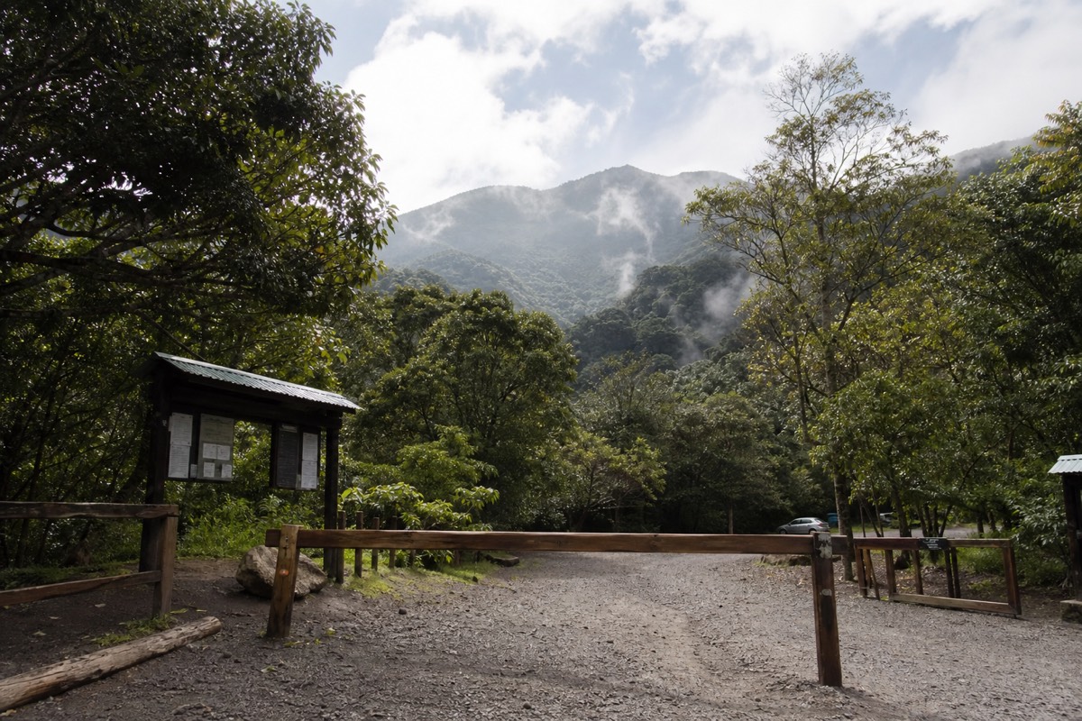 Entrance gate area of Cerro Verde national park with forest and volcanic slopes behind, morning haze