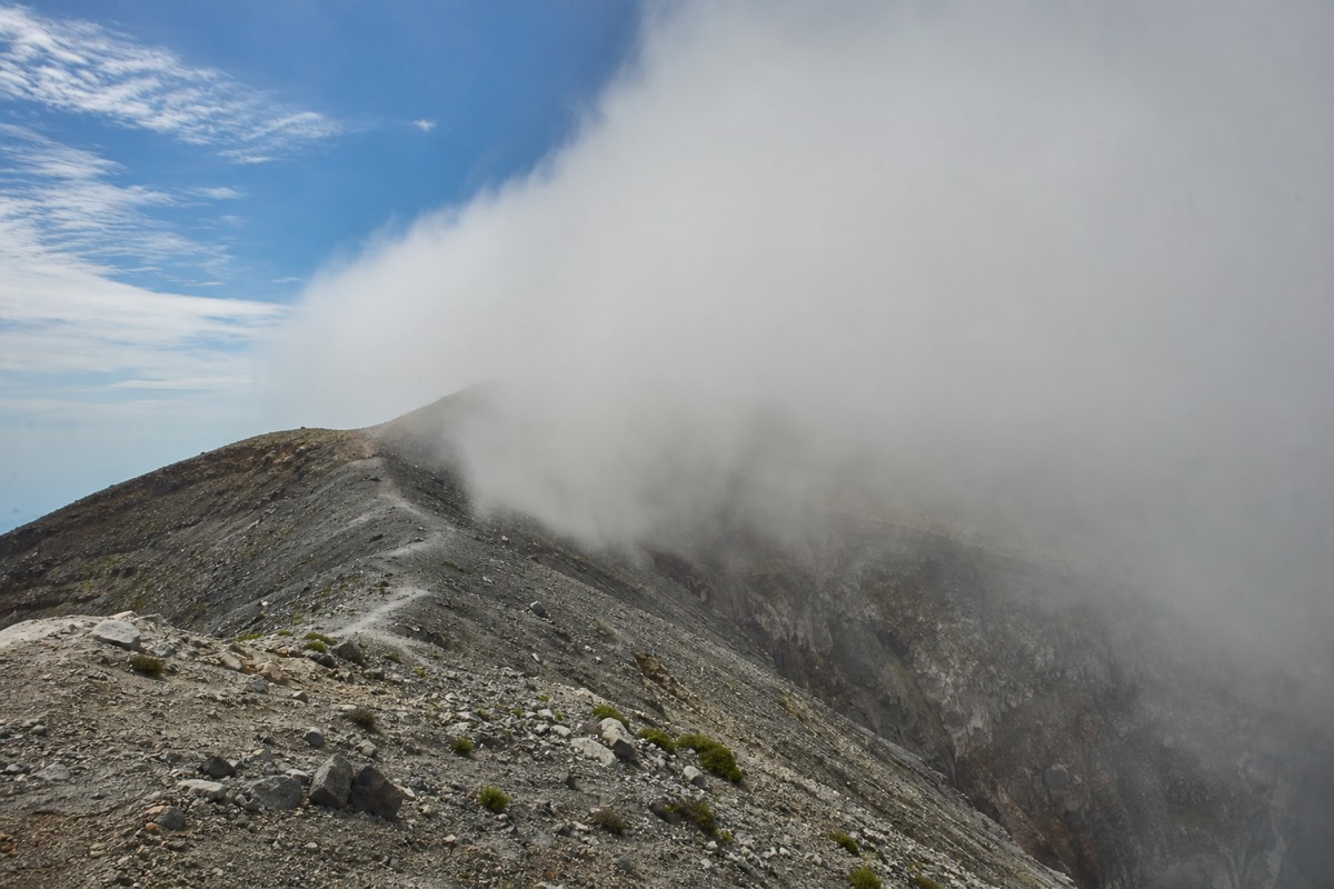 Afternoon cloud building over the rim of Santa Ana volcano with the trail fading into mist