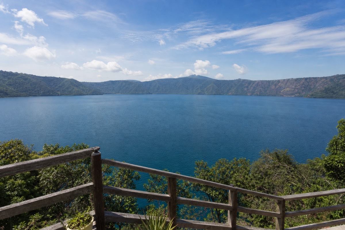 Calm blue water of Lake Coatepeque, El Salvador, seen from a lakeside terrace with volcanic caldera walls in the distance