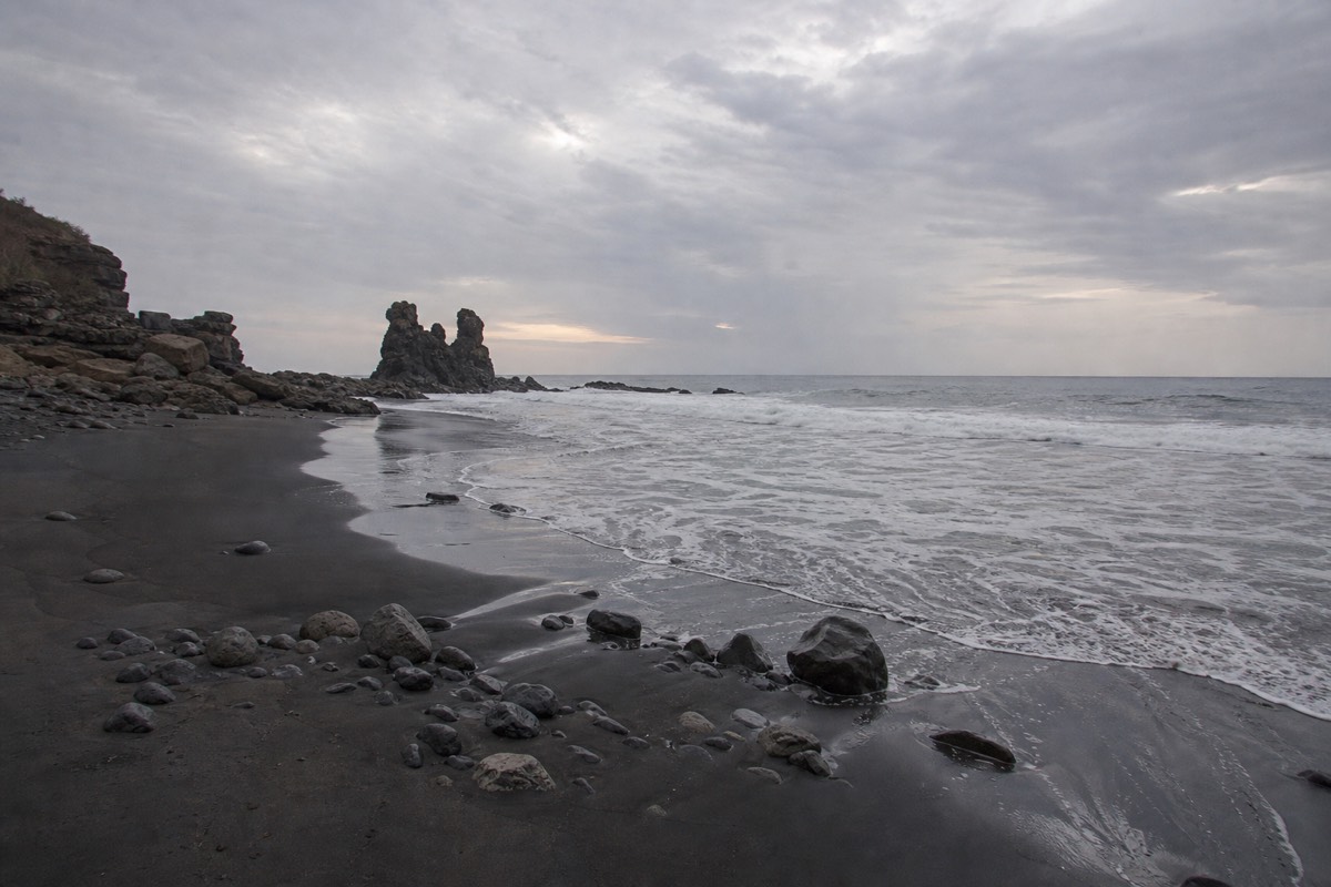 Grey dawn light over the black sand and rock stacks of El Tunco beach before the day's heat